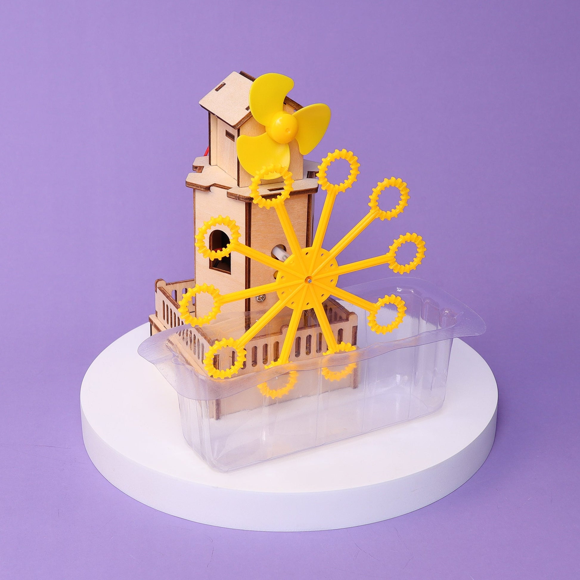 Wooden model of a DIY Bubble Machine Kit with a yellow propeller and gear system on a purple background