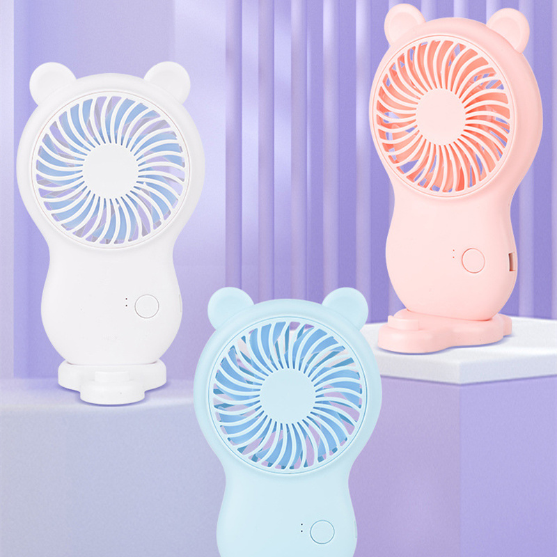 Three bear-shaped handheld fans in white, blue, and pink on a light purple background.