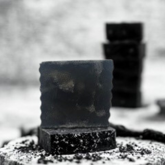 Stack of black soap bars on a textured surface with a blurred background