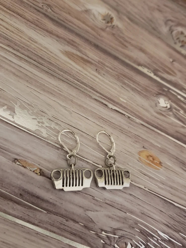 Silver jeep grille earrings on a wooden surface