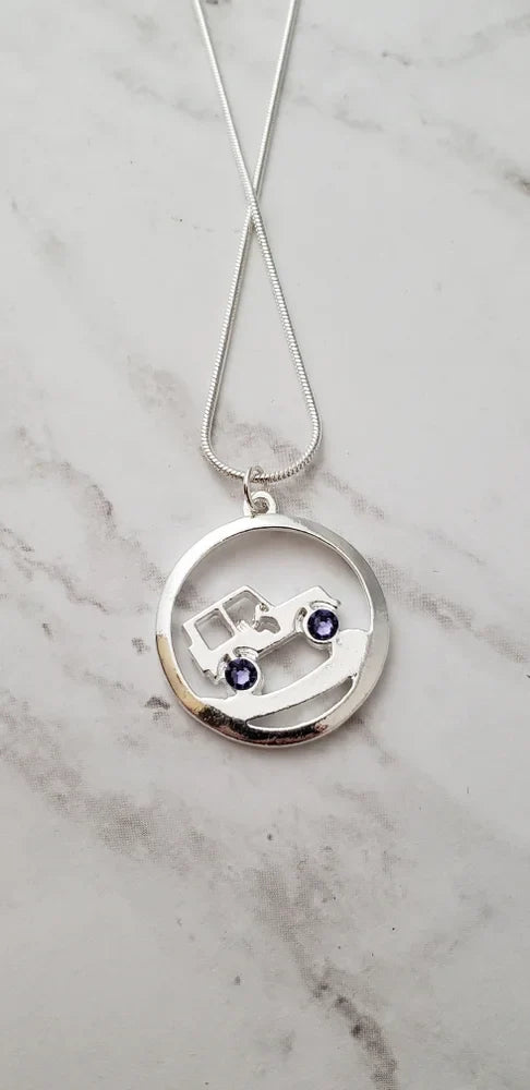 Silver necklace with a circular pendant on a marble background