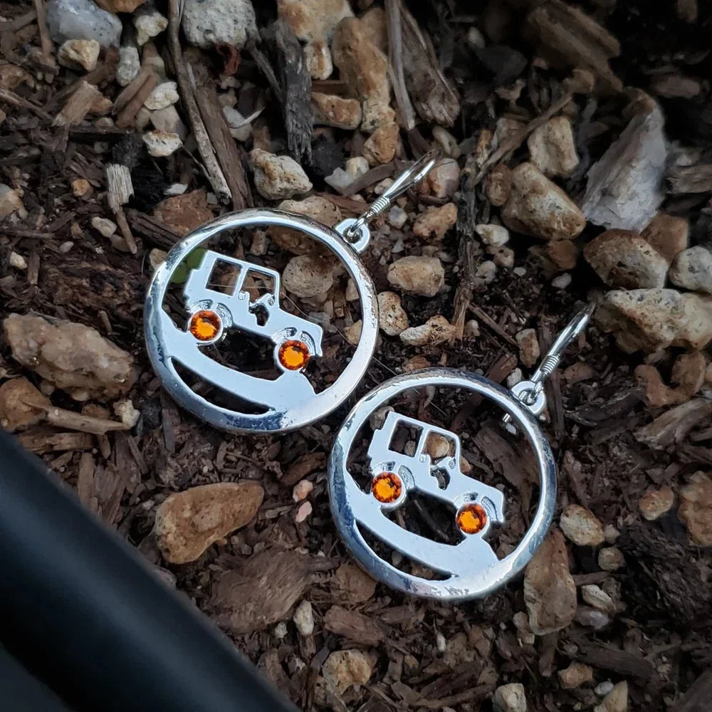 Silver earrings with orange stones on a rocky surface