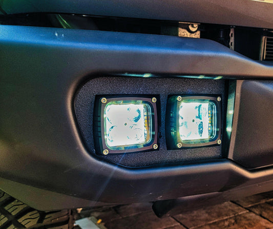 Close-up of a vehicle's front bumper with two square lights.