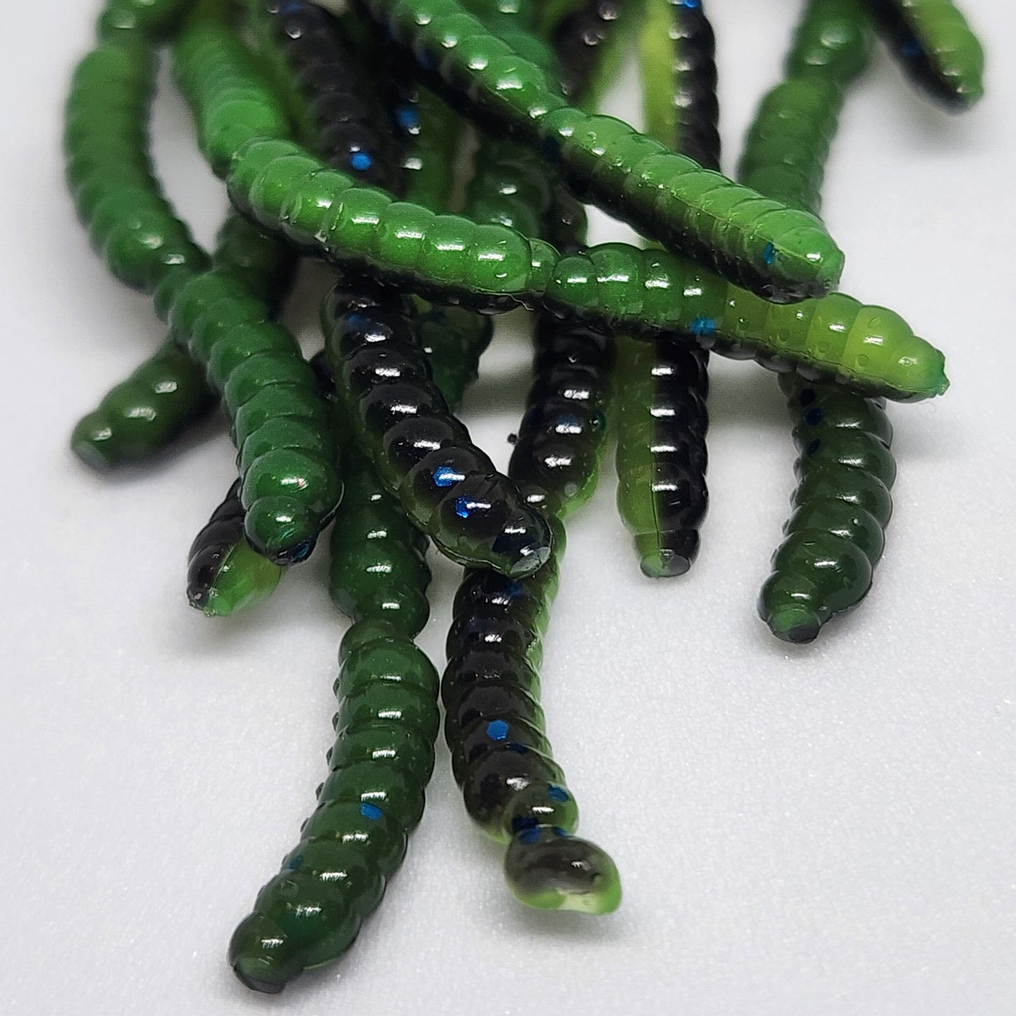 Green and black fishing lures on a white background