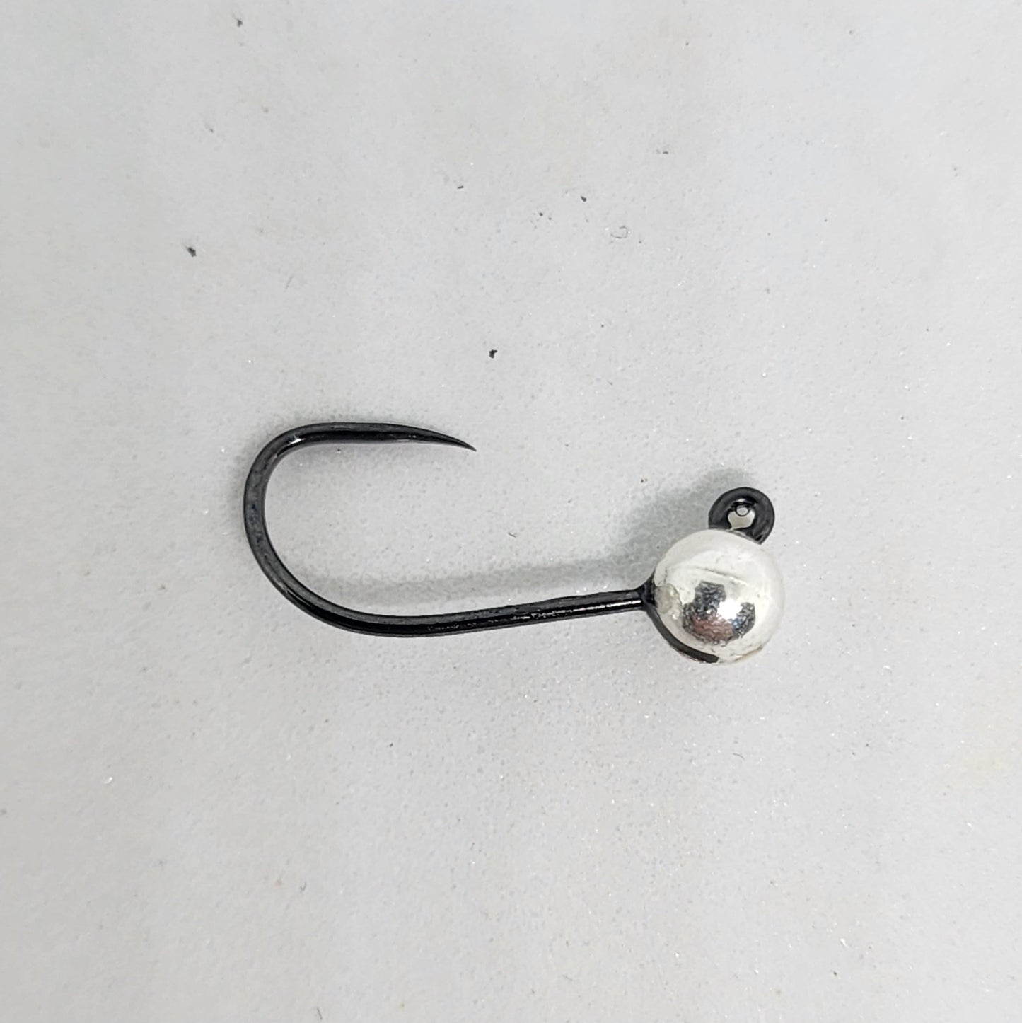 Fishing hook with a silver ball on a gray background