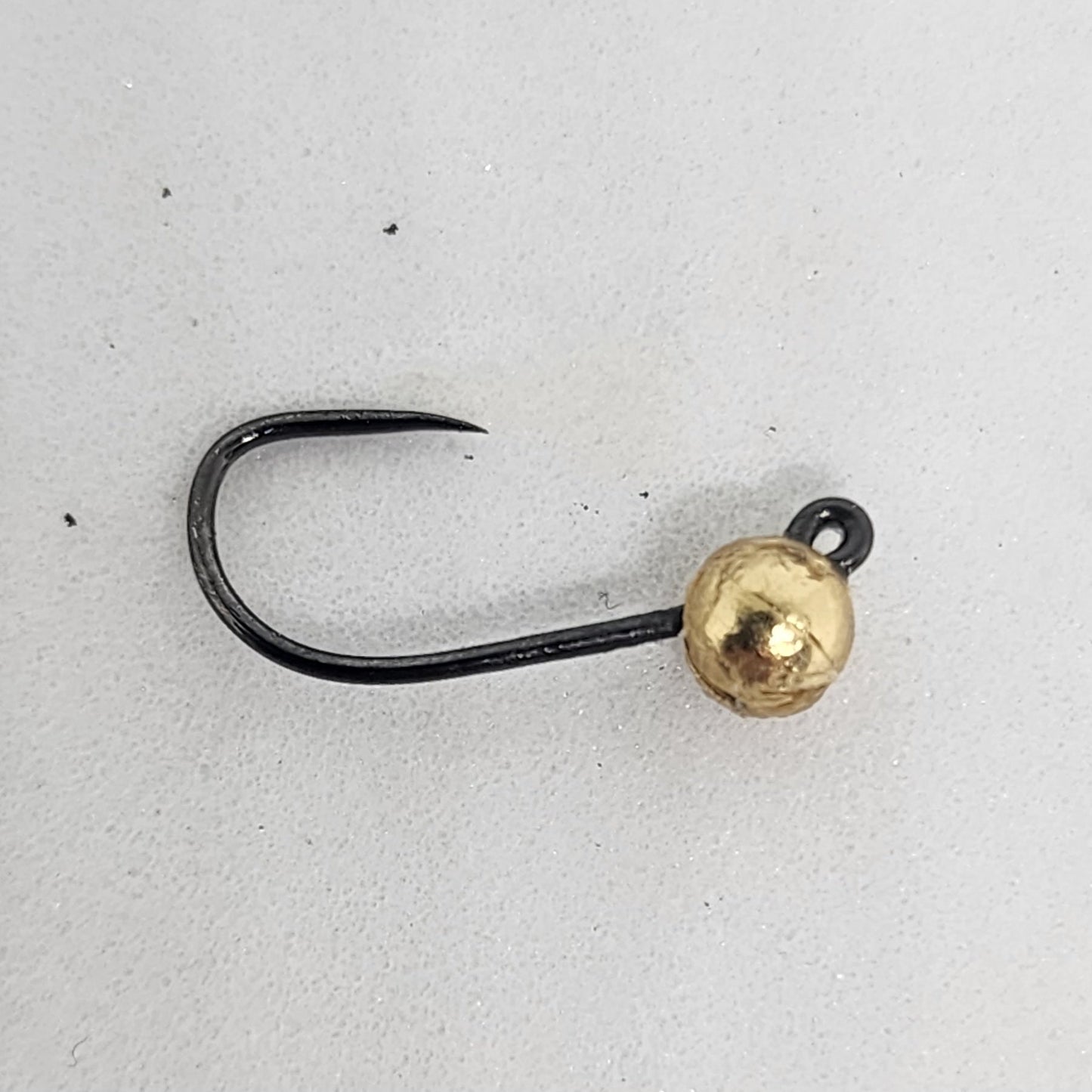 Fishing hook with a gold bead on a light gray background