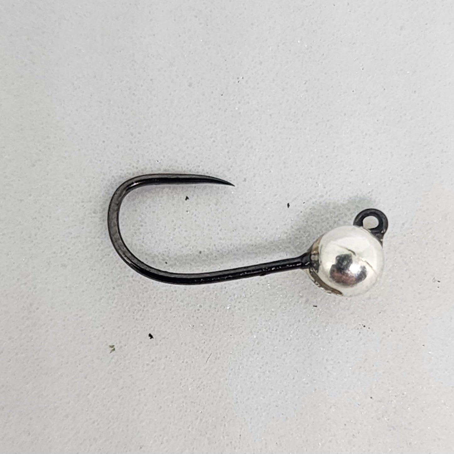 Fishing hook with a silver bead on a light gray background