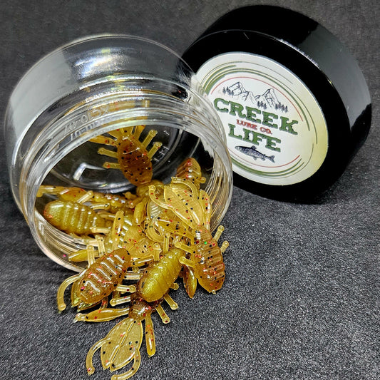Jar of crawfish-shaped fishing lures with 'Creek Life' container on a dark surface