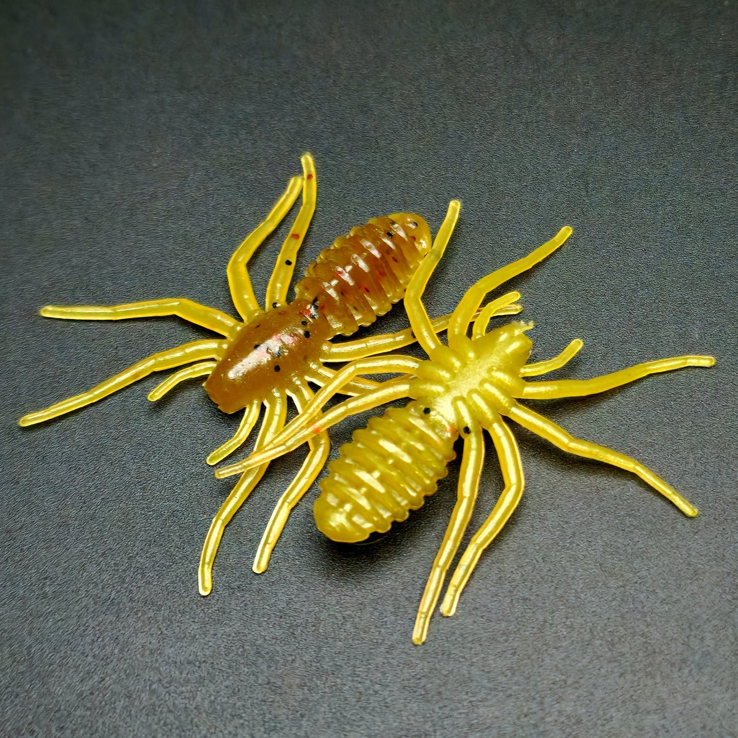 Two yellow spider-like fishing lures on a dark gray background
