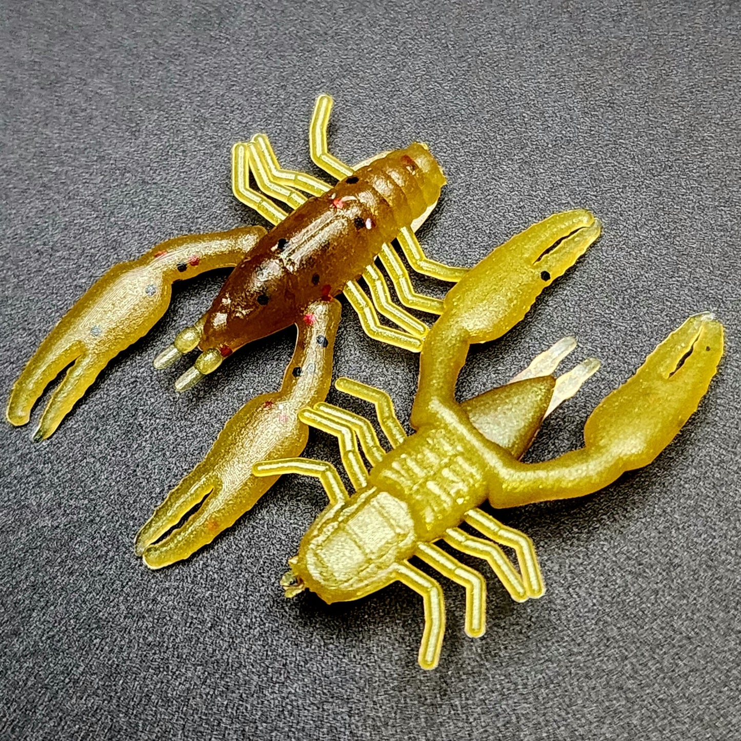 Three yellow and brown crawfish lures on a gray background