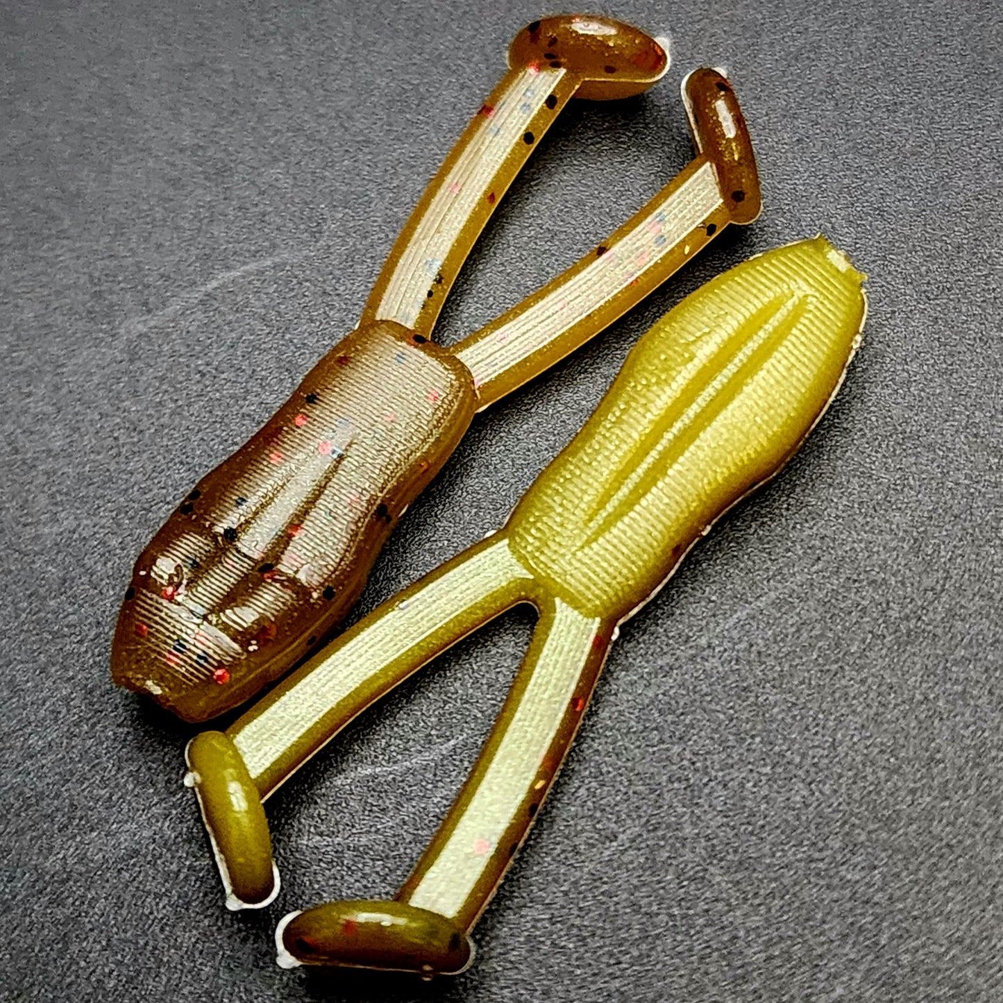 Two fishing lures with a brown and yellow color scheme on a gray background
