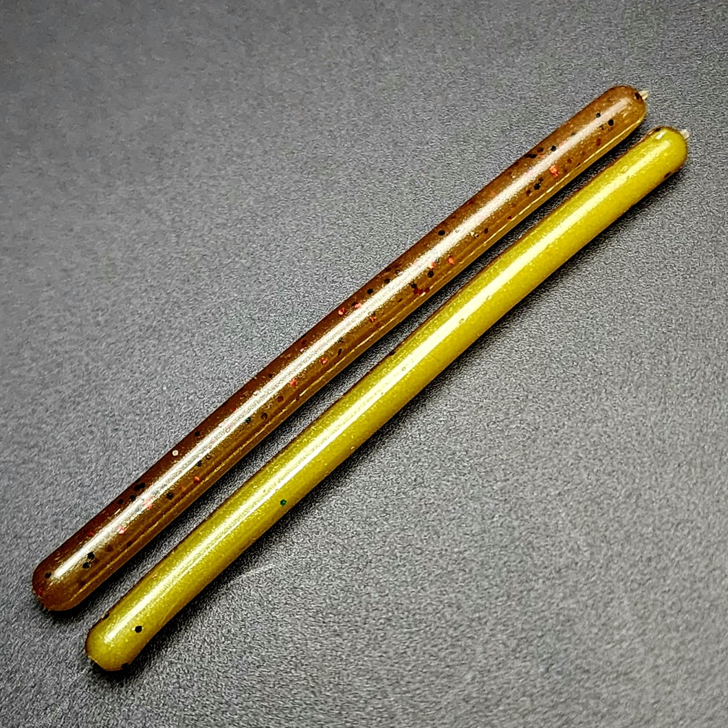 Two fishing lures, one brown and one yellow, on a gray surface