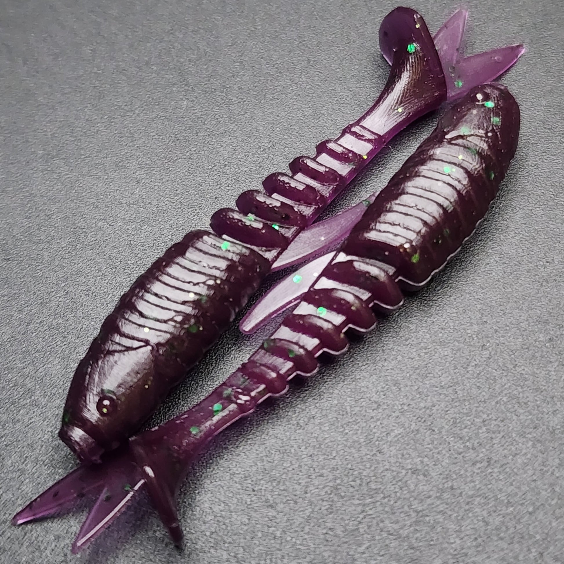 Two purple fishing lures on a gray surface