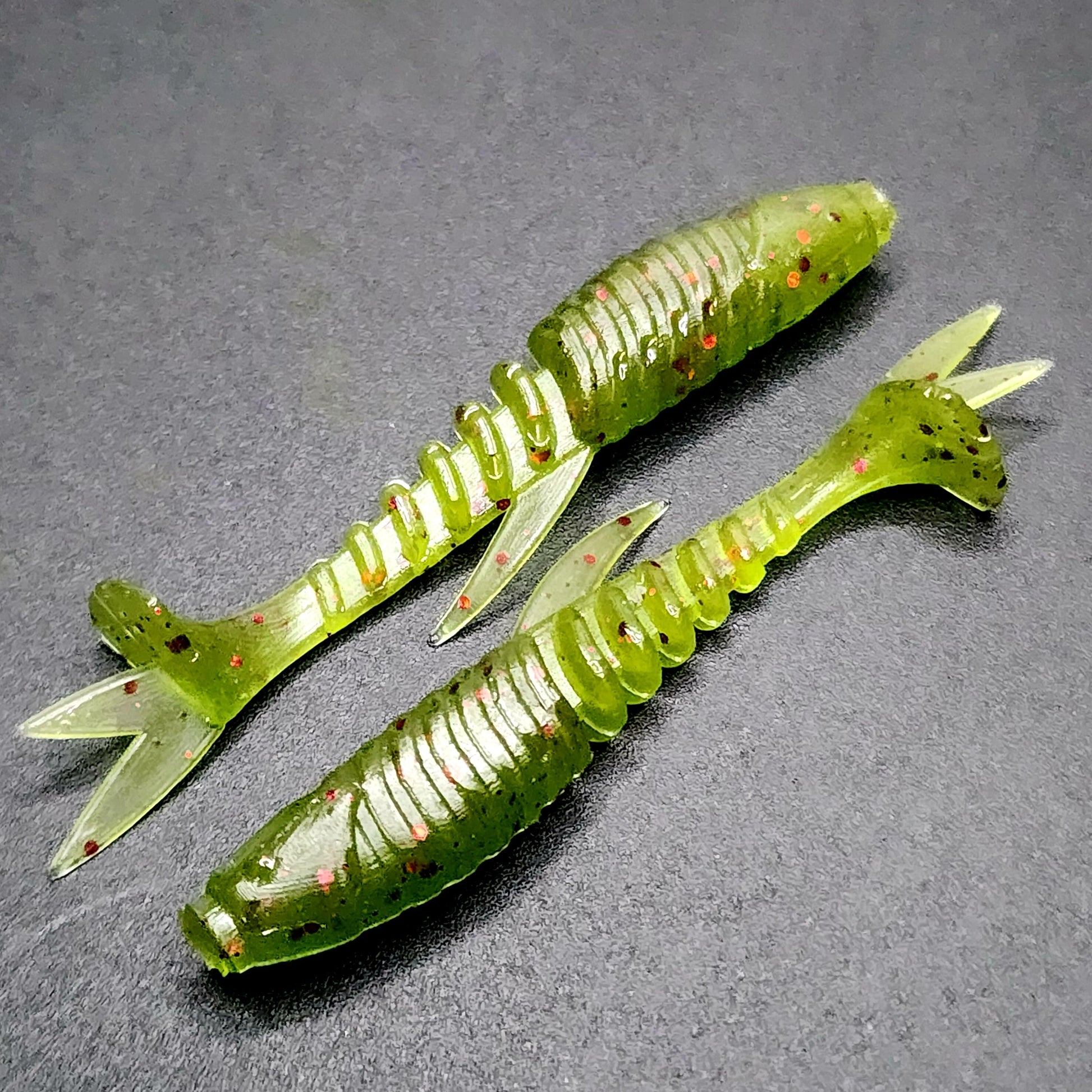 Two green fishing lures on a gray surface