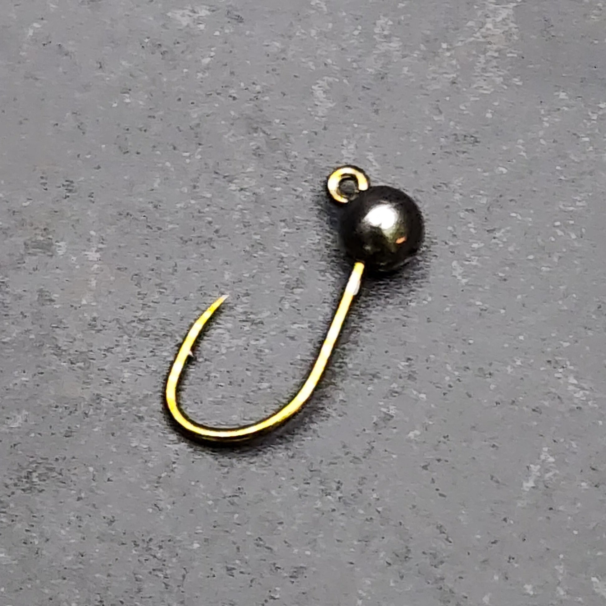 Fishing hook with black bead on a gray surface