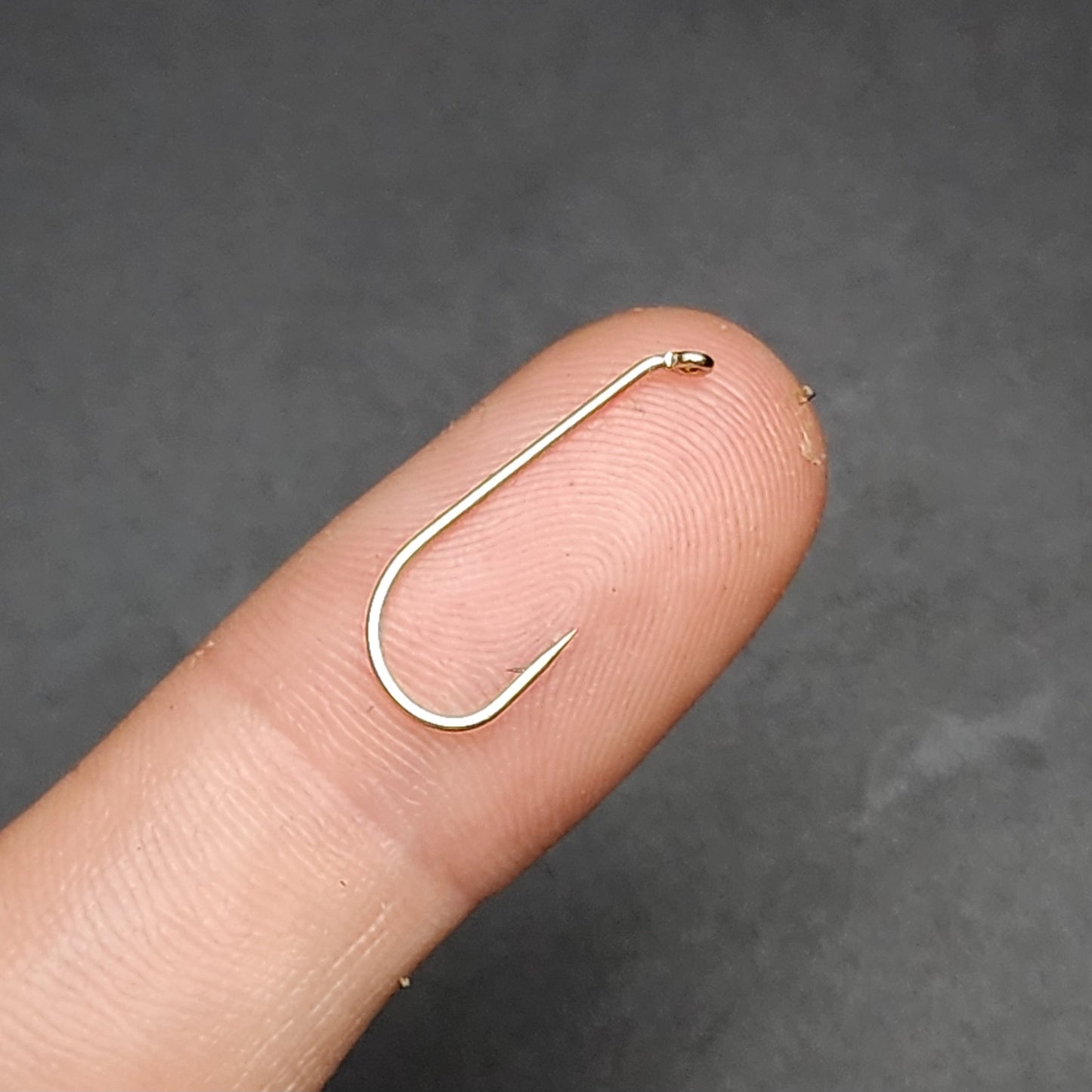 Fish Hook on a finger against a dark background