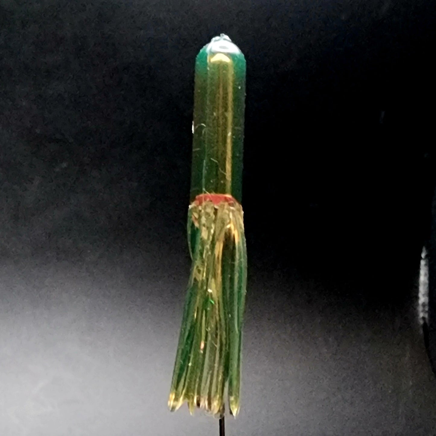 Green and gold fishing lure on a dark background