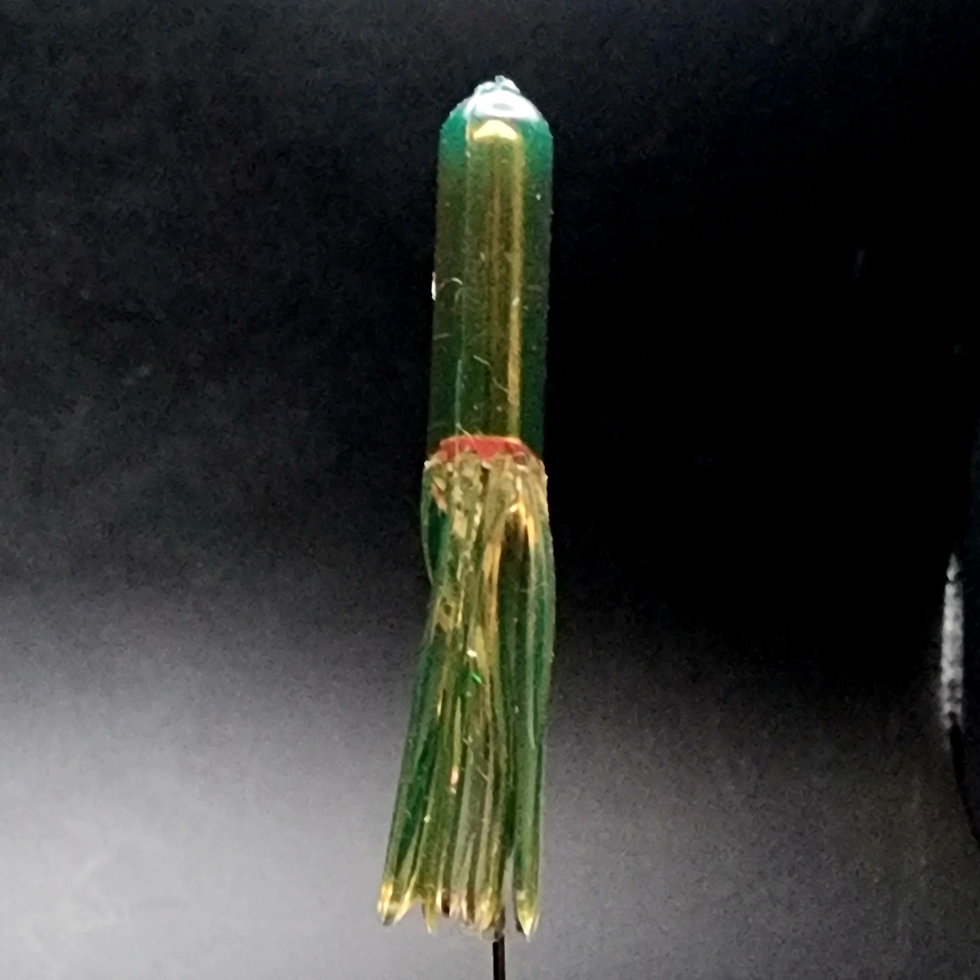 Green and gold fishing lure on a dark background