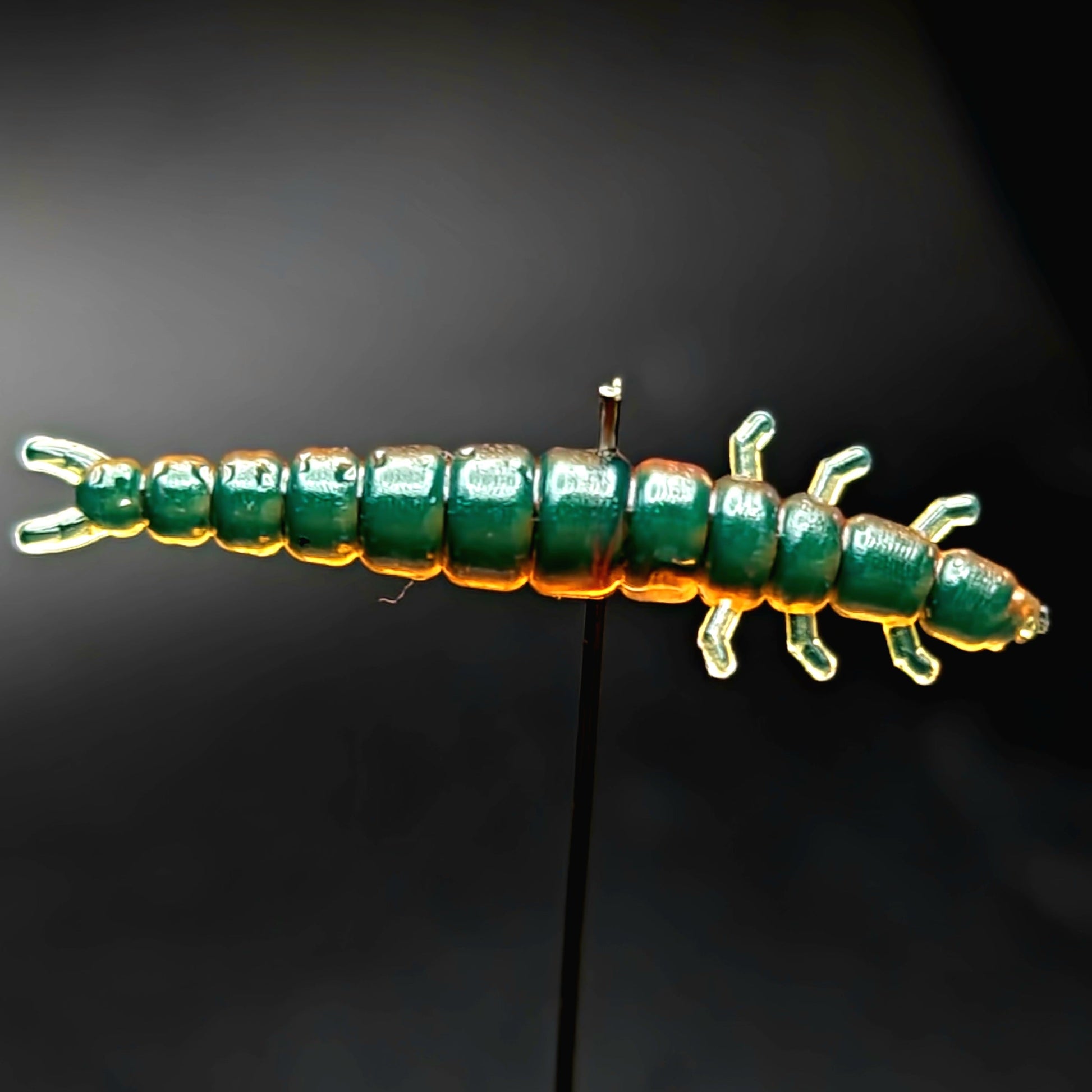 Green and orange segmented fishing lures on a black background