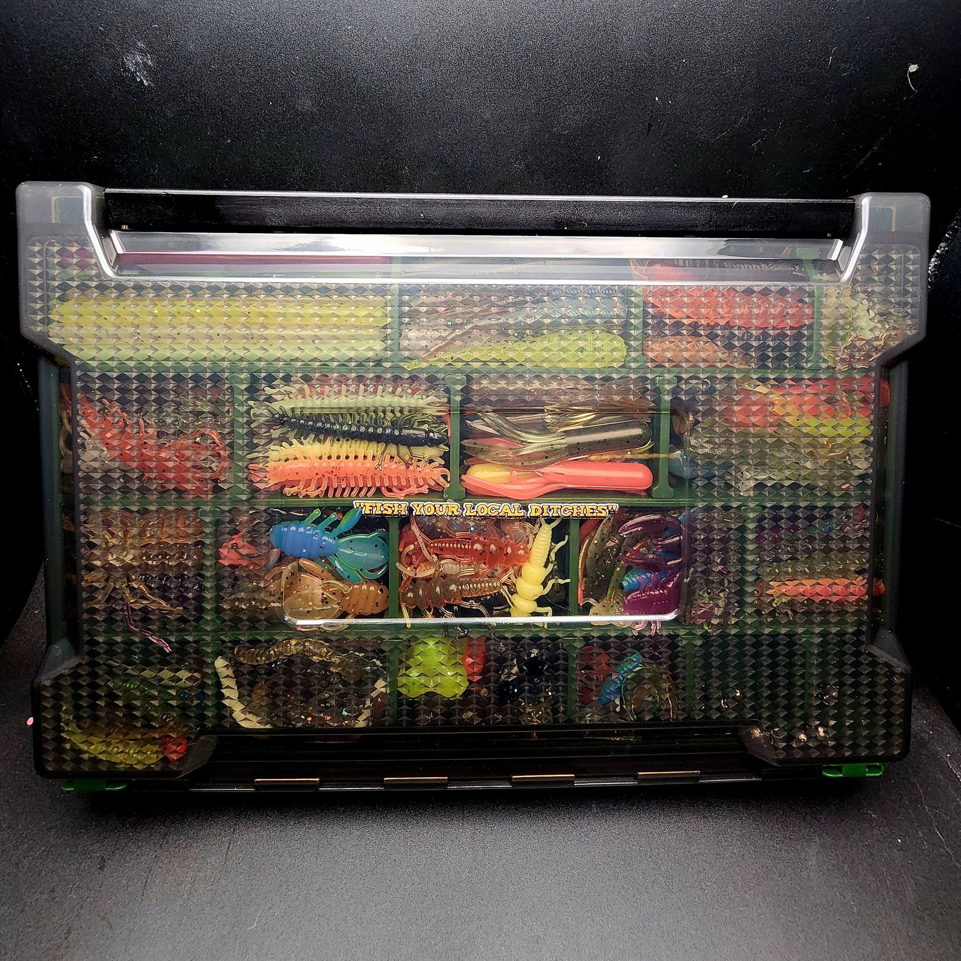 Container with various colorful fishing lures on a dark background