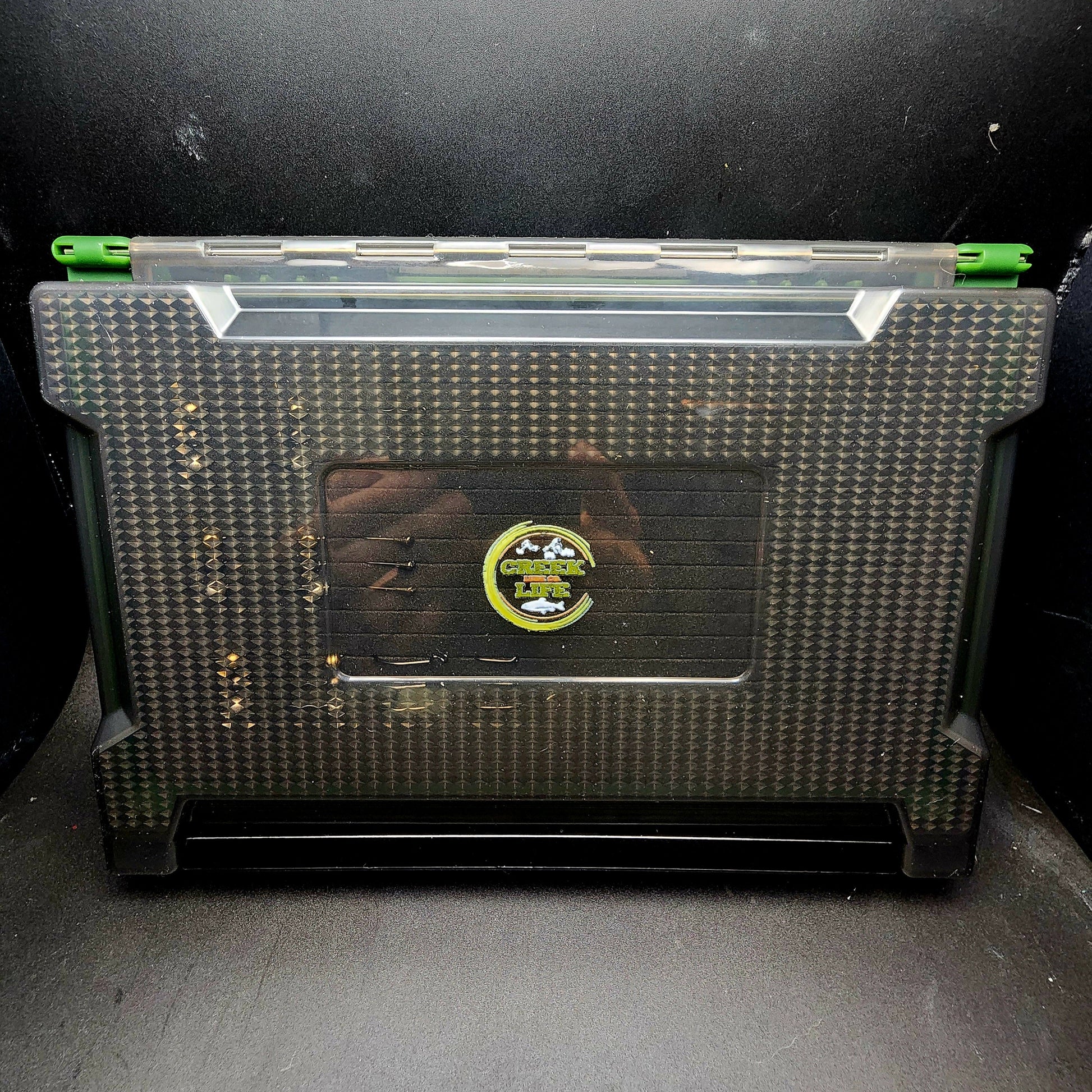 Black and green storage box with a visible brand logo on a dark background