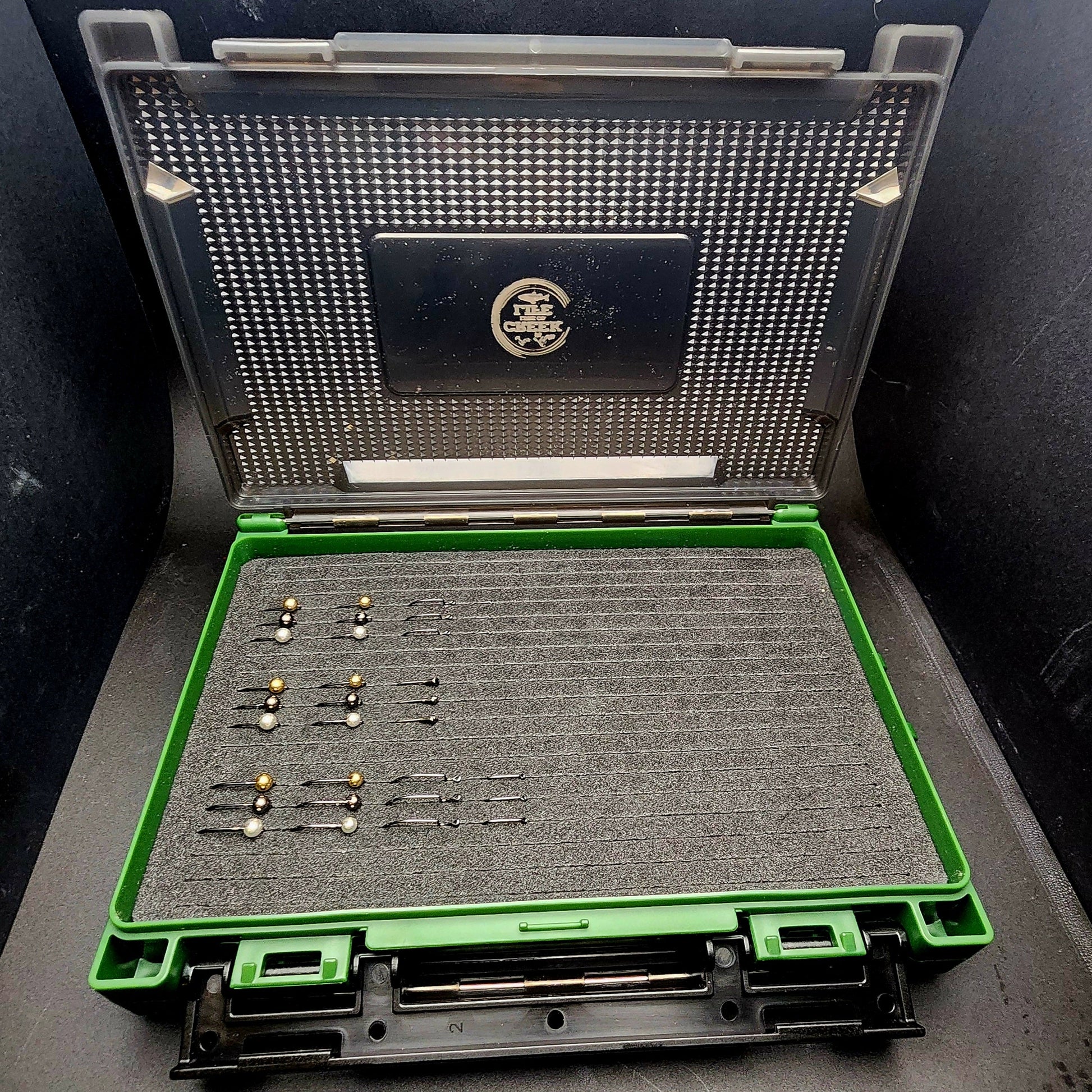 Open case with fishing lures on a dark surface