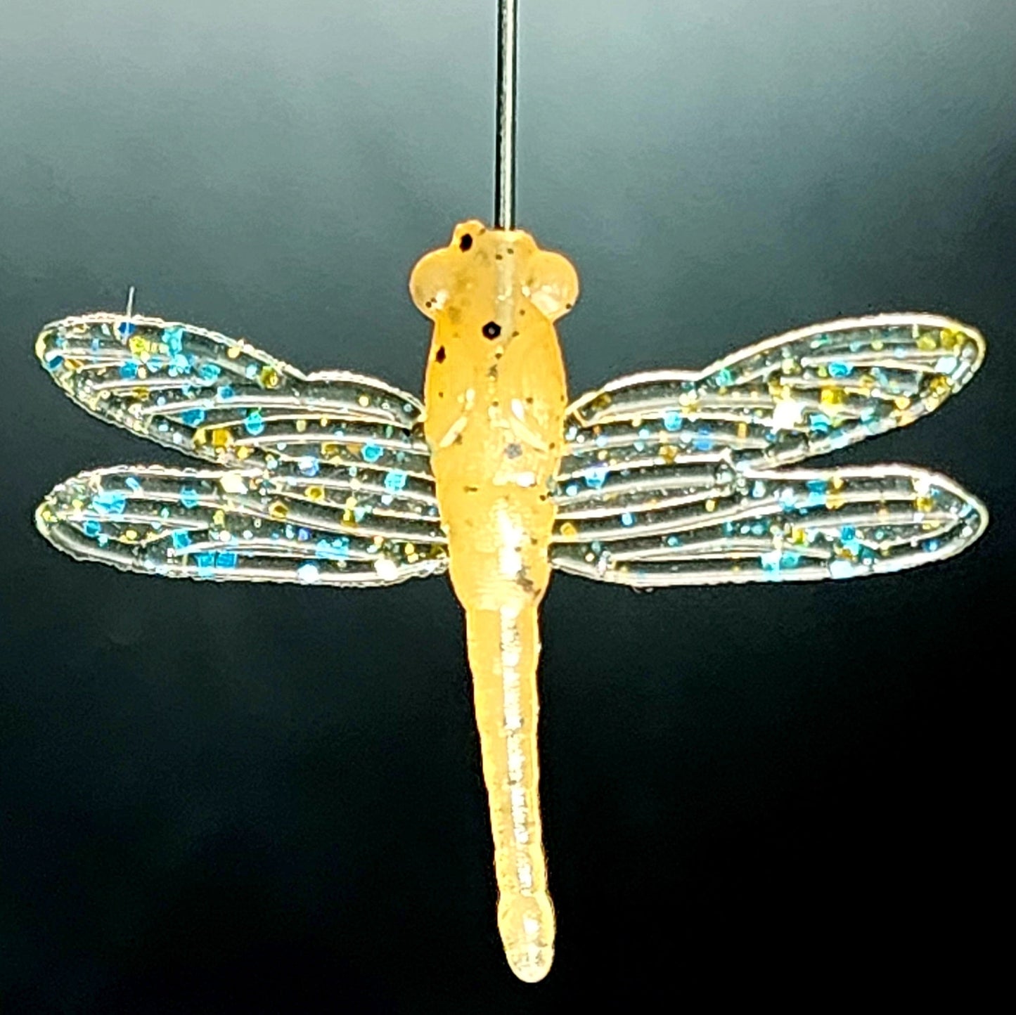 Decorative dragonfly ornament with beaded wings on a dark background