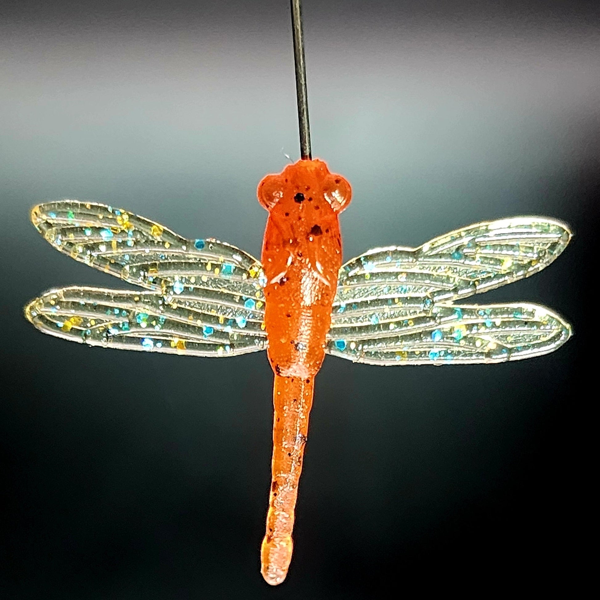 Orange dragonfly fishing lure on a black background