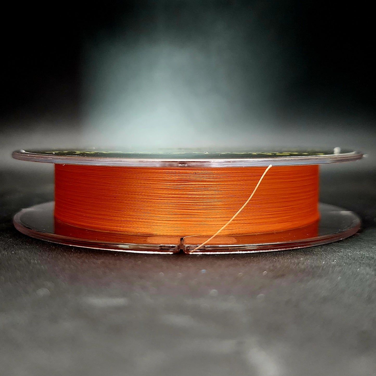 Spool of orange fishing line on a dark background