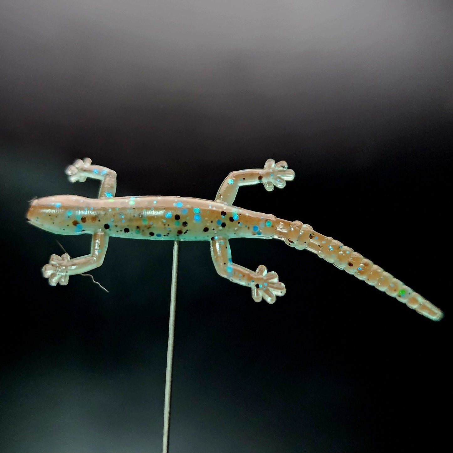 Glowing lizard-shaped object on a black background