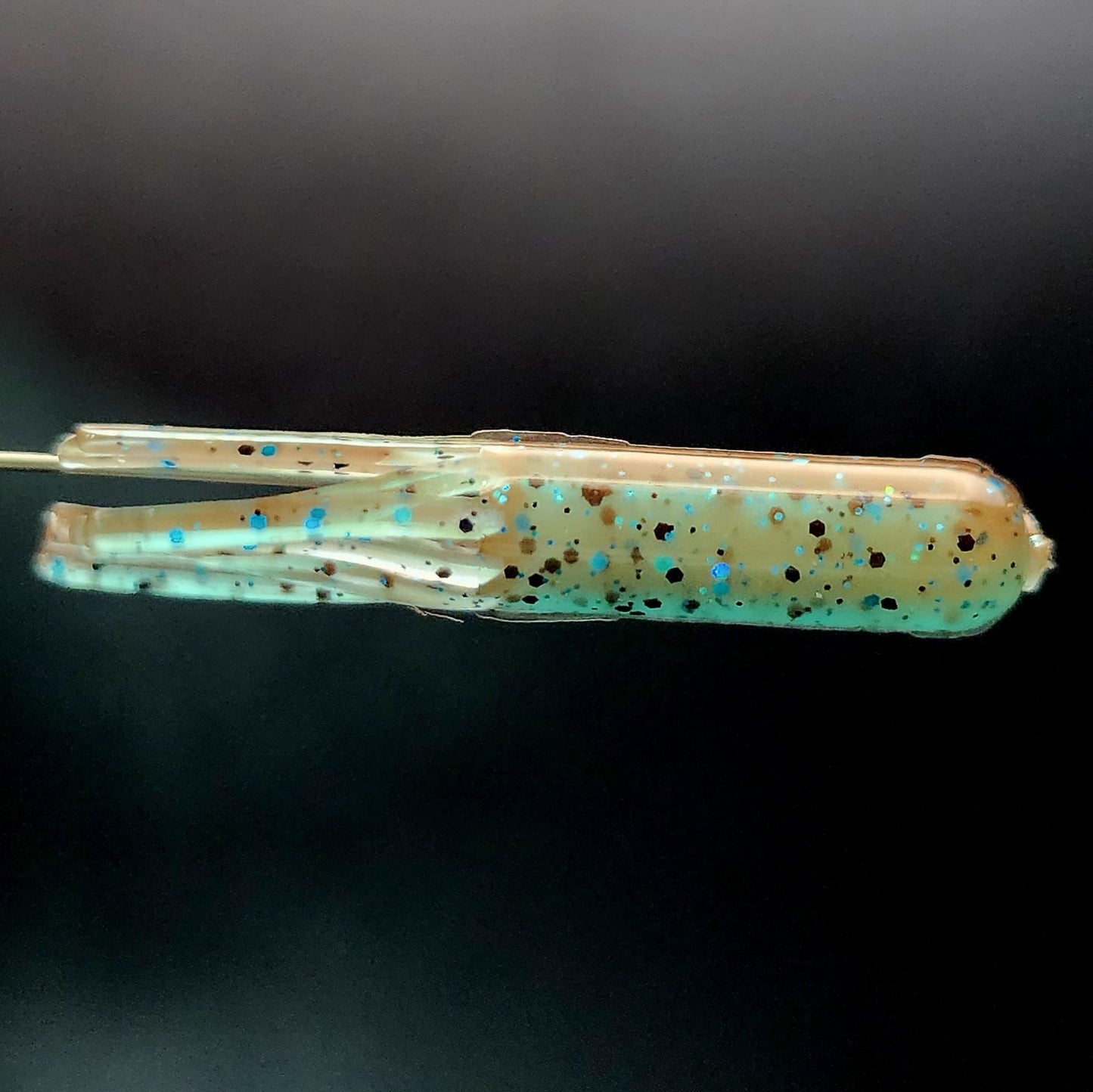 Fishing lure with speckled pattern on a black background