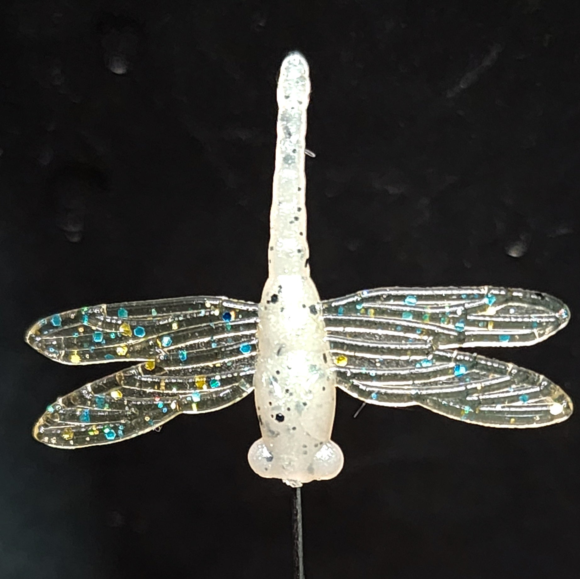 Dragonfly fishing lure with glittery wings on a black background