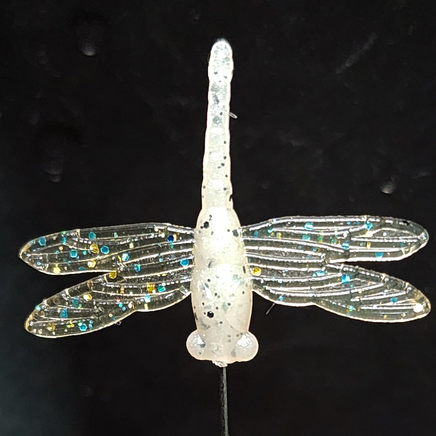 Dragonfly fishing lure with glittery wings on a black background