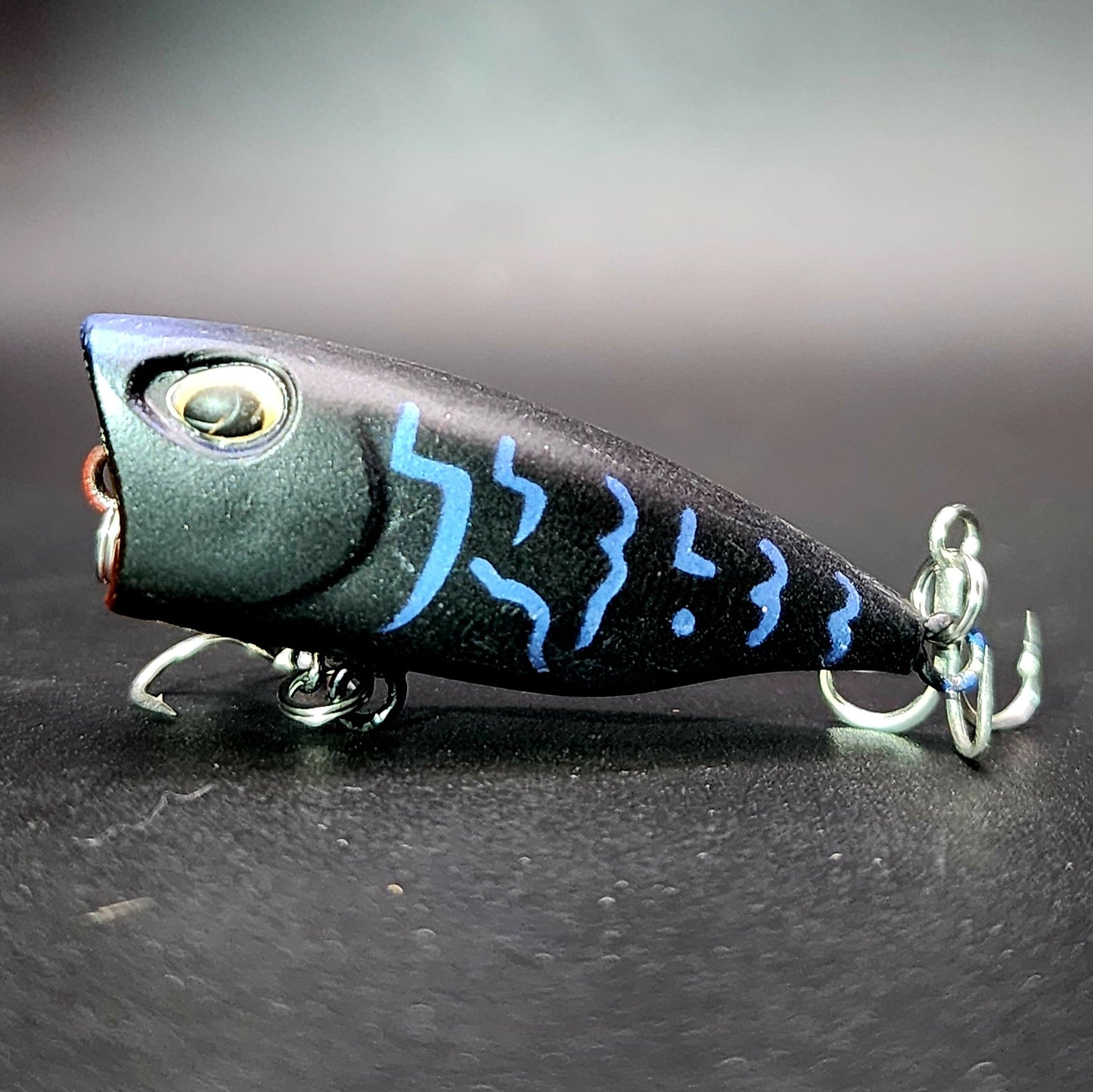 Fishing lure with blue patterns on a dark surface
