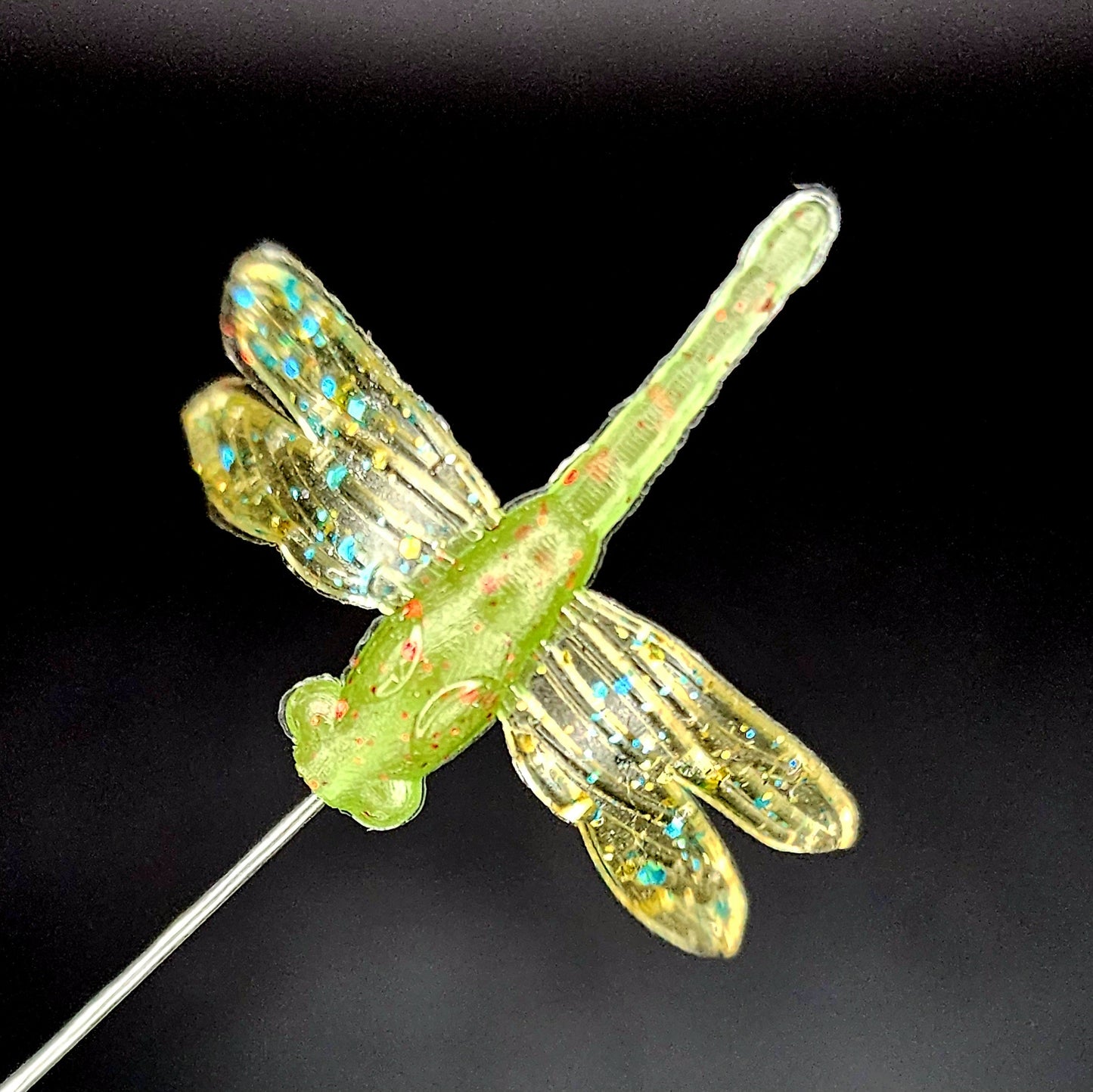 Green dragonfly-shaped fishing lure on a black background