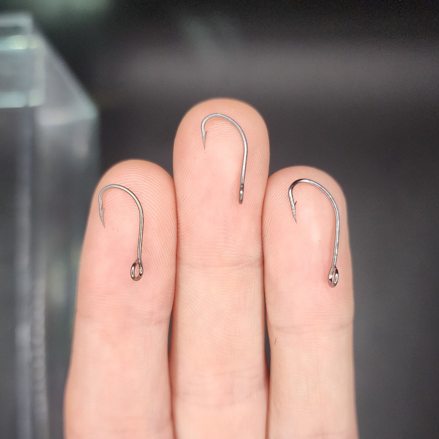 Three fishing hooks on a person's fingers with a blurred background