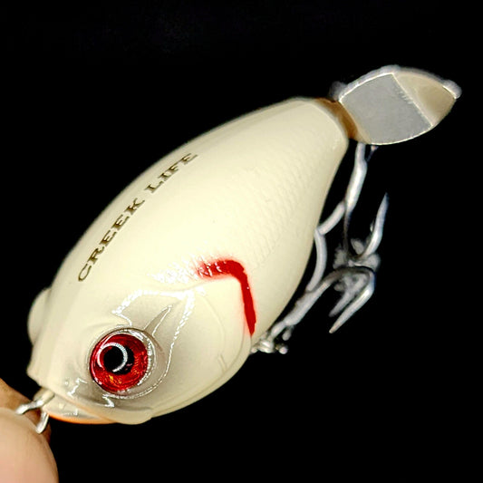 Fishing lure with 'Creek Life' branding on a black background