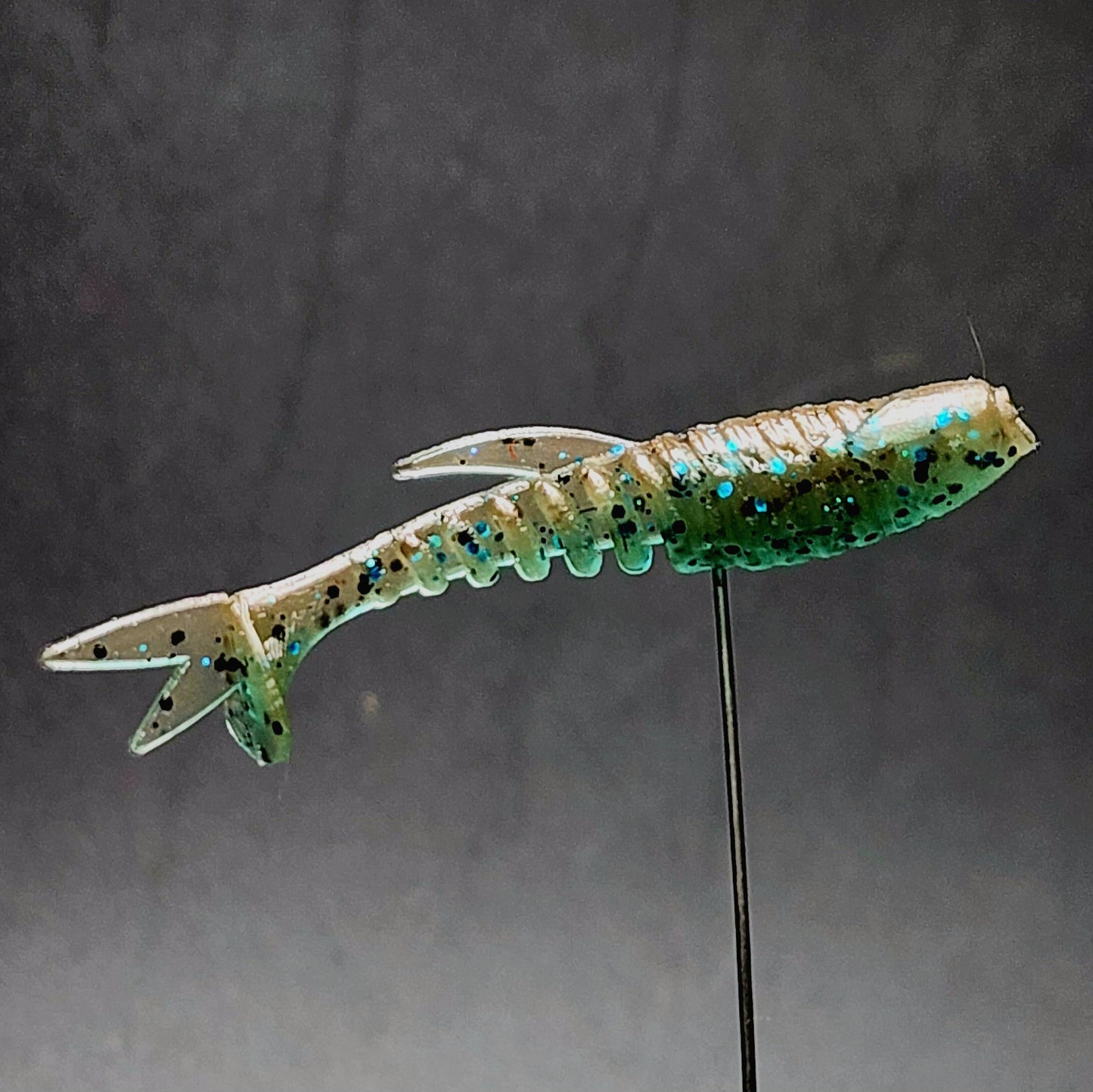 Fishing lure with a green and beige pattern on a dark background