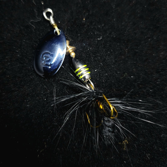 Fishing lure with blue teardrop shape and gold and black details on a dark background