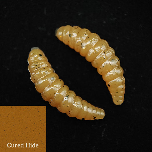 Two yellowish-brown larvae lures on a black background with 'Cured Hide' label.
