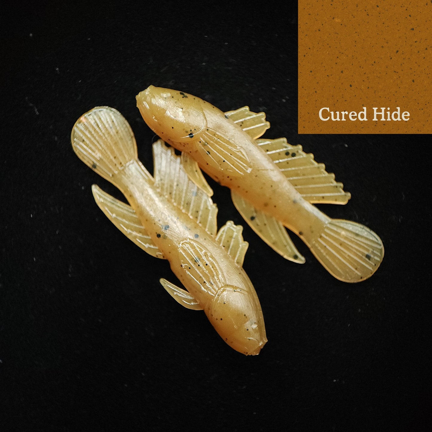 Two yellow fish-shaped fishing lures on a black background with 'Cured Hide' text.