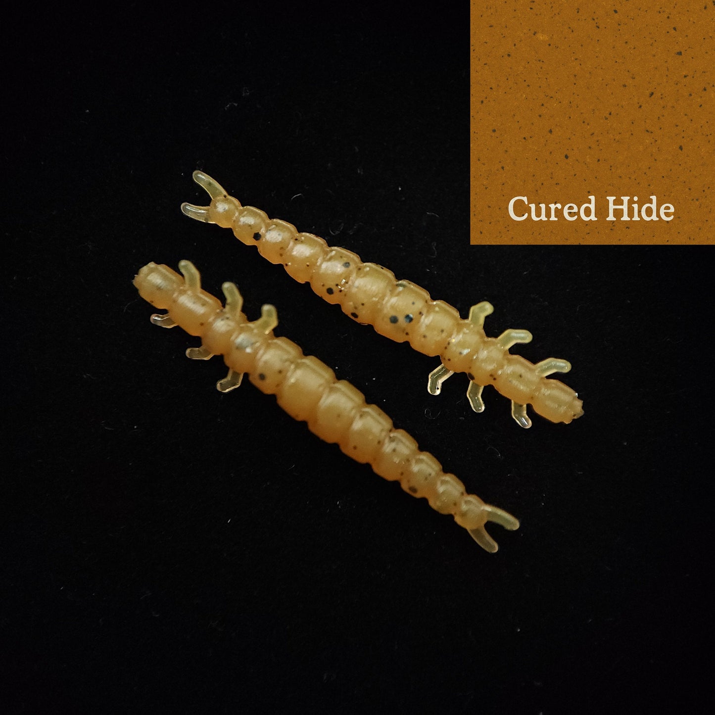 Two yellow larva-like fishing lures on a black background with 'Cured Hide' text.