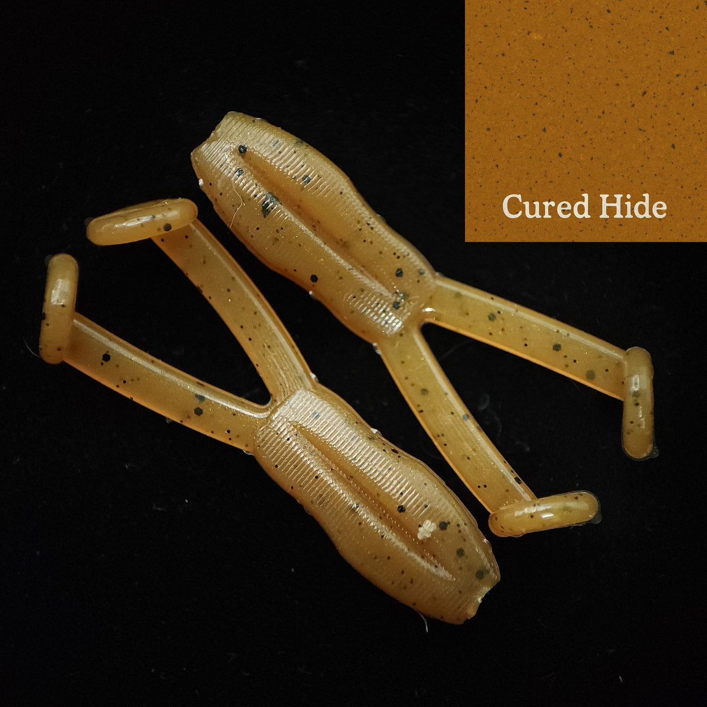 Yellowish-brown fishing lure with speckles on a black background, labeled 'Cured Hide'.