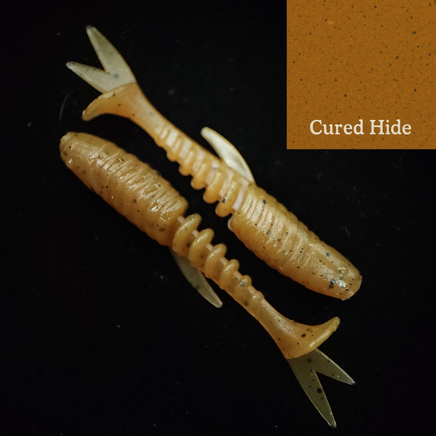 Two fishing lures with a 'Cured Hide' label on a dark background
