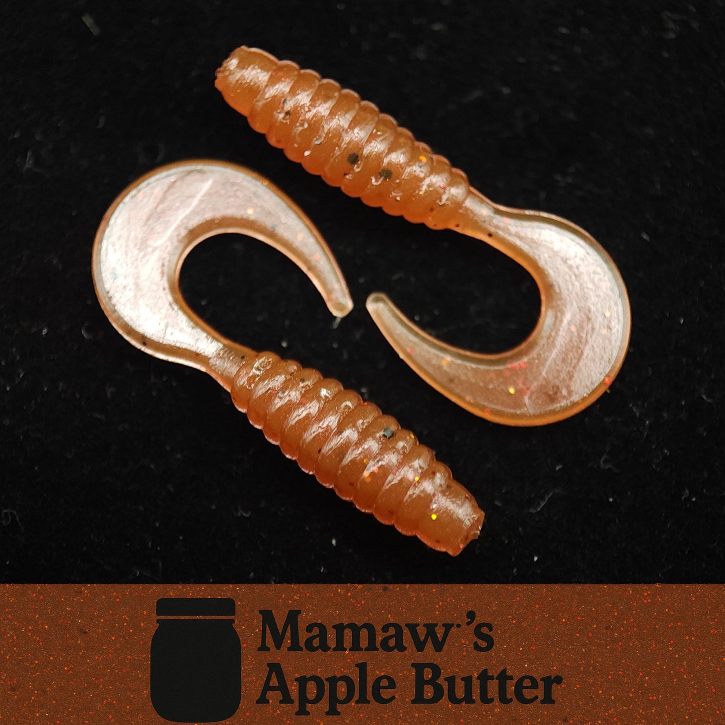 Two soft plastic fishing lures with a clear hook on a black background, branded 'Mamaw's Apple Butter'.