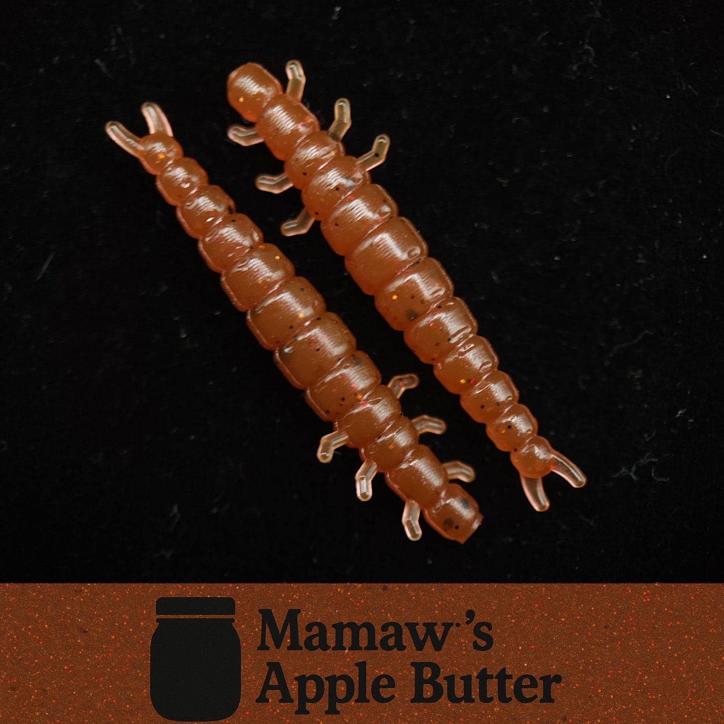 Two brown centipede fishing lures on a black background with 'Mamaw's Apple Butter' logo.