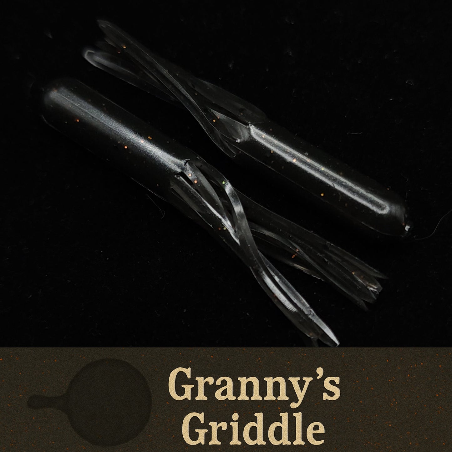 Black fishing lures with 'Granny's Griddle' branding on a dark background
