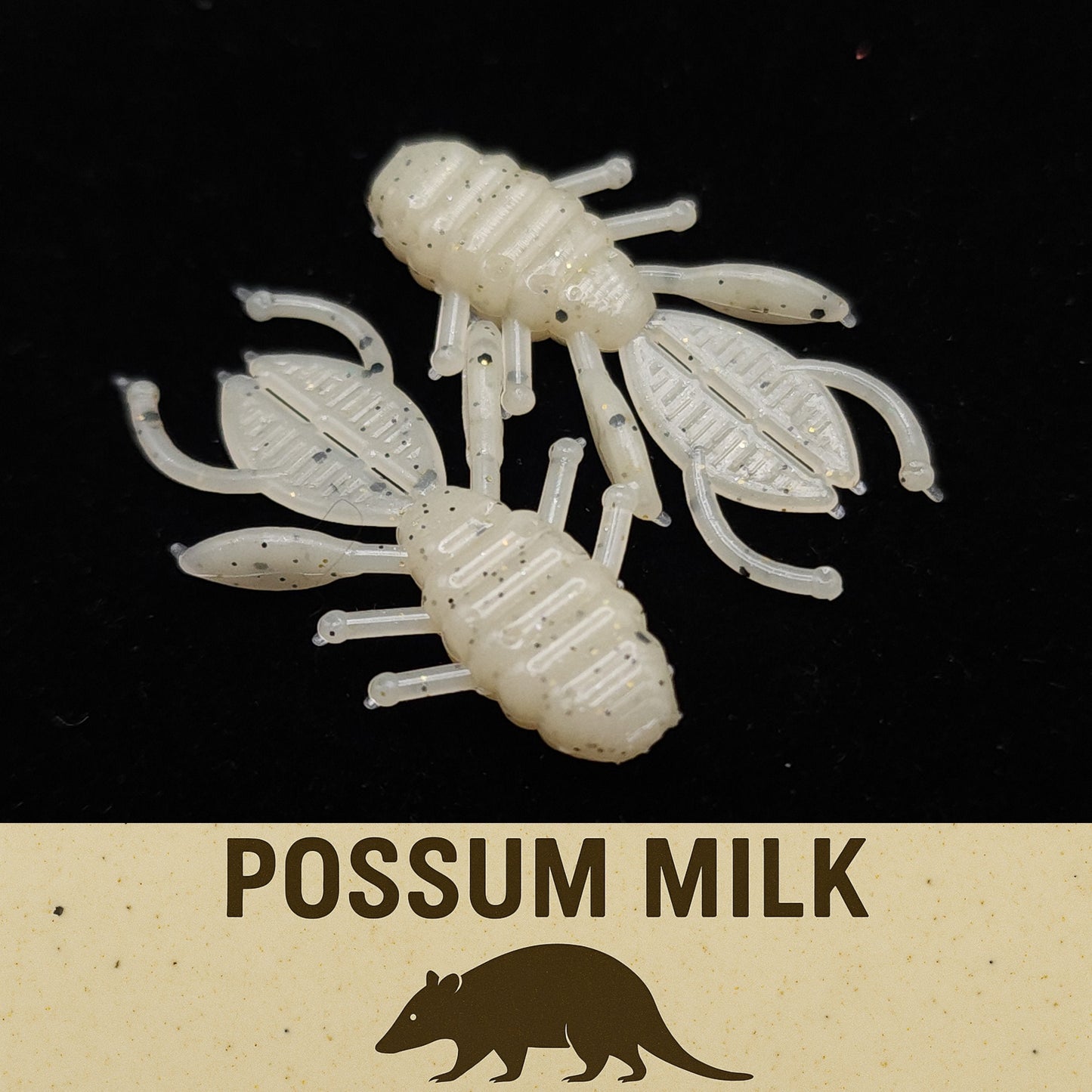 Two white crawfish-shaped fishing lures on a black background with 'Possum Milk' text.