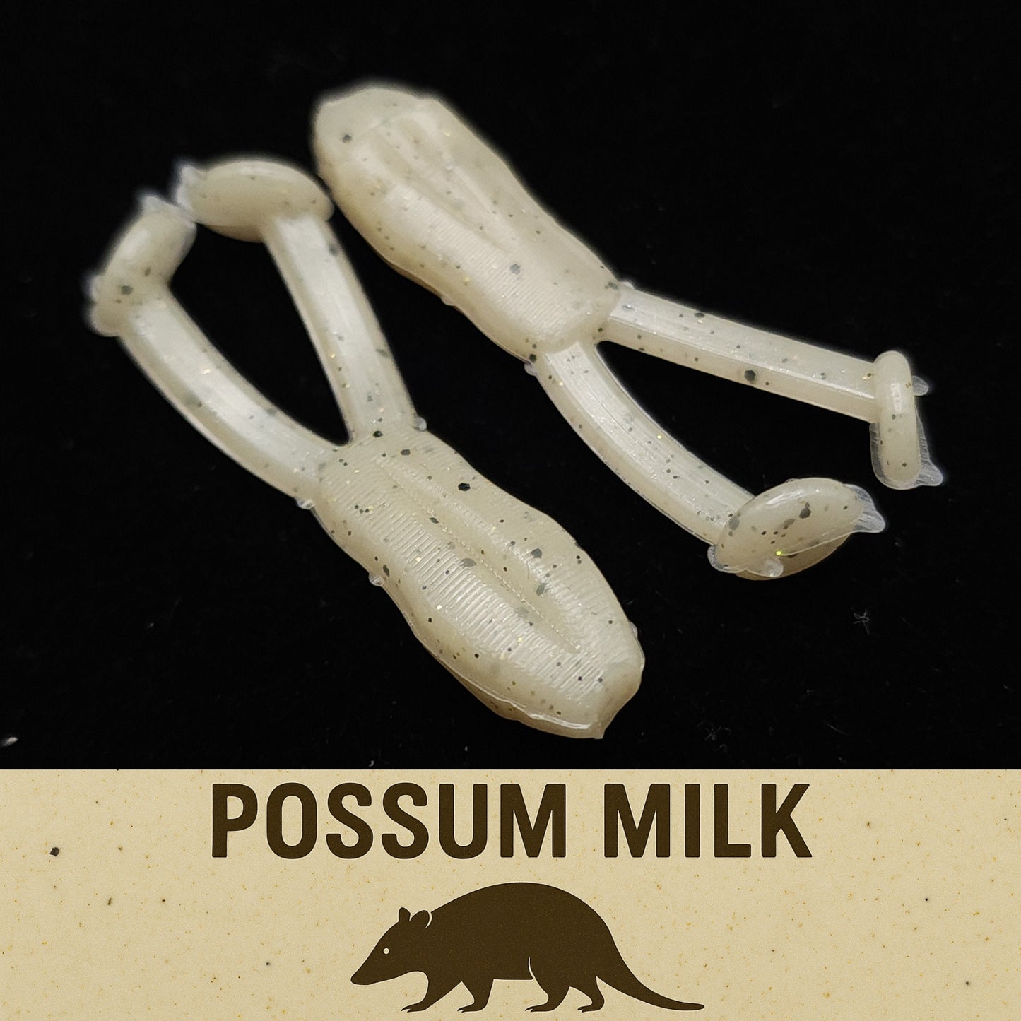 Two white fishing lures with specks on a black background, labeled 'Possum Milk'.