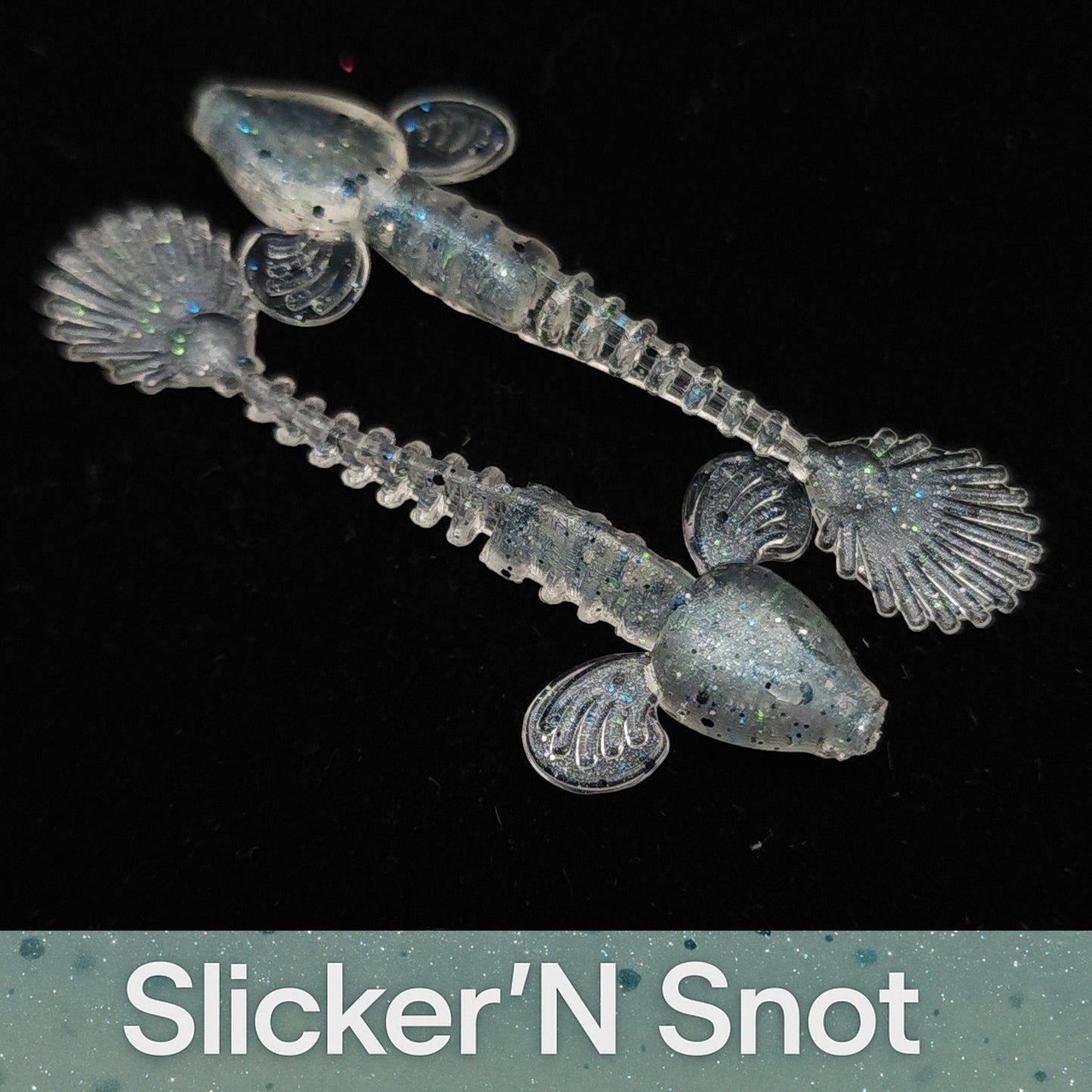 Transparent plastic toys with shell-like ends on a black background, branded 'Slicker'N Snot'.